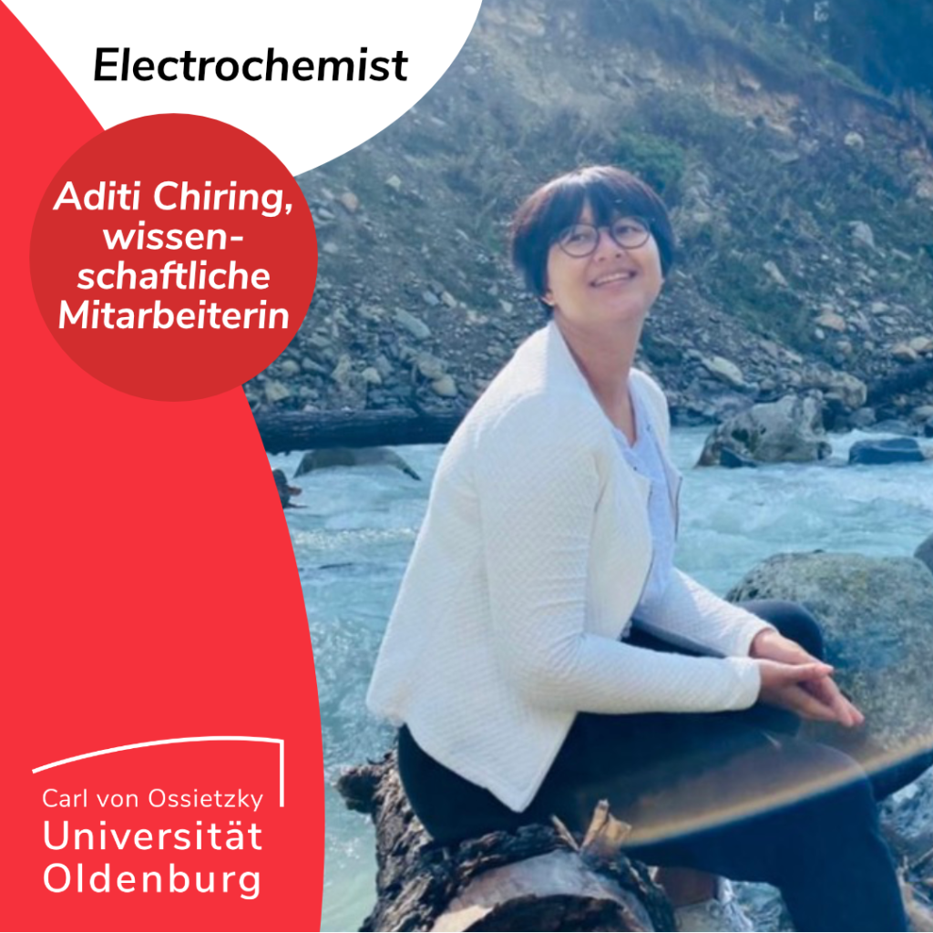 Electrochemist Aditi Chiring, wissenschaftliche Mitarbeiterin 
Aditi Chiring is sitting on a a tree trunk in front of a river in front of a mountain. She is wearing a white jacket and a blue shirt and ist smiling at the camera. She is wearing glasses and has ear-long dark hair and bangs. 

