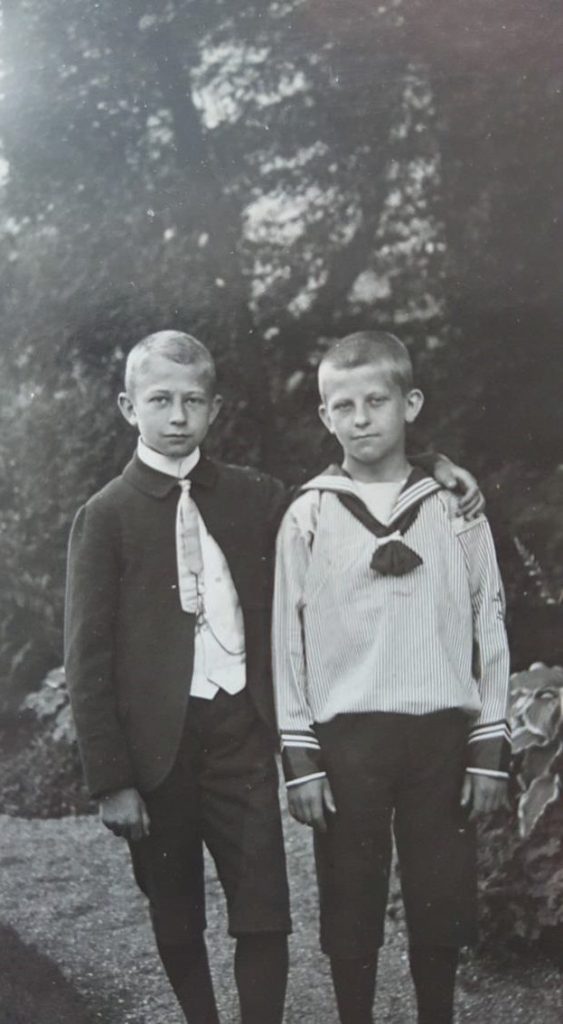 Schwarz-weiß Bild von zwei Jungen. Der eine hat seinen Arm über die Schultern des Anderen gelegt. 